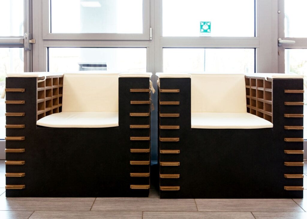 Fauteuil convertible en carton avec bancs modulaires et tiroirs intégrés, idéal pour les espaces professionnels et les salles de pause dans les entreprises. Structure en panneaux cartonnés renforcés, plateau haut et sièges ergonomiques pour un confort optimal - Le Meuble en Carton une marque du groupe Natur Design