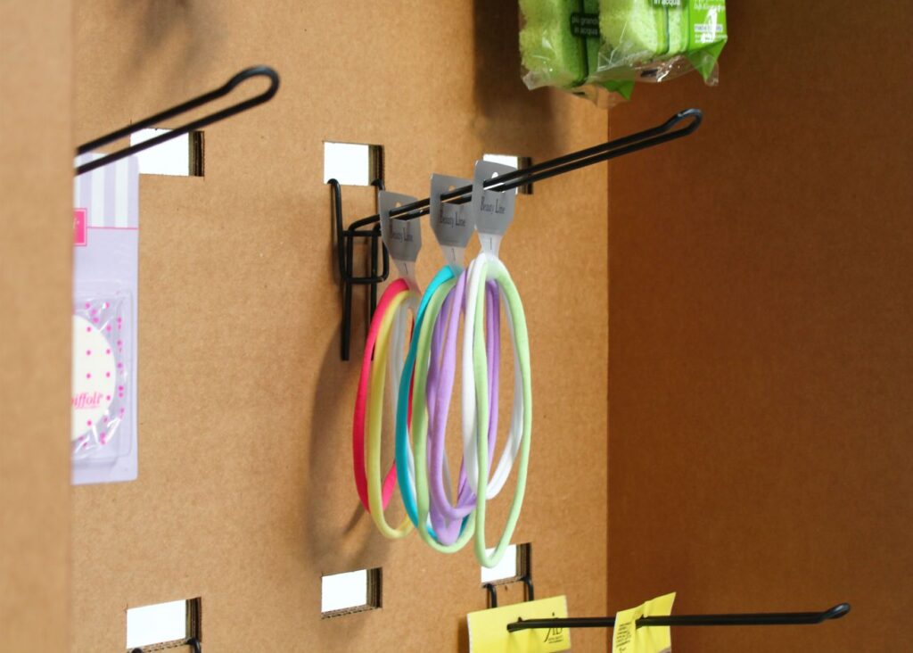 Présentoir en carton écologique suspendu avec charnières métalliques et supports pour affiches ou produits, adapté à l’aménagement de magasins, stands événementiels et scénographie professionnelle - Le Meuble en Carton une marque du groupe Natur Design