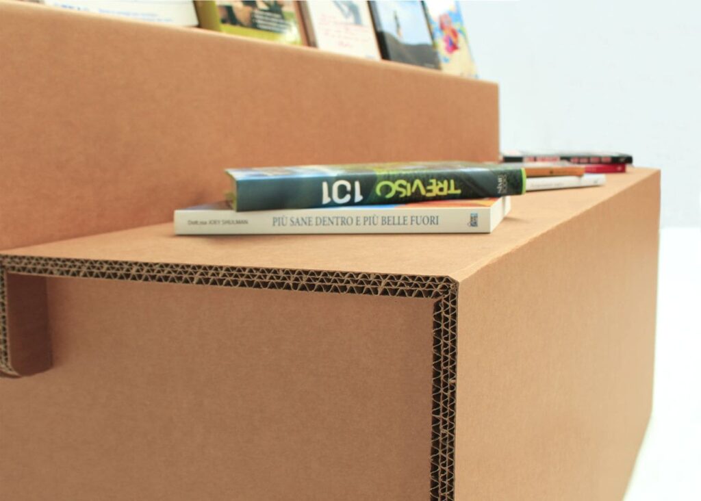 Présentoir à livres en carton pour l'aménagement de magasins, structure solide et esthétique avec livres disposés en rangée sur plateau cartonné, idéal pour la mise en valeur des ouvrages dans les espaces commerciaux - Le Meuble en Carton une marque du groupe Natur Design