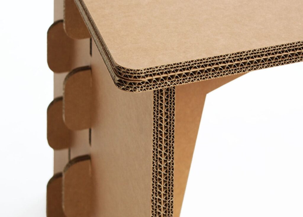 Détail d'un bureau en carton écologique pour aménagement d'entreprise, avec structure solide composée de panneaux cartonnés renforcés et charnières métalliques visibles sur les côtés, idéale pour bureaux et espaces collaboratifs ou salles de pause - Le Meuble en Carton une marque du groupe Natur Design