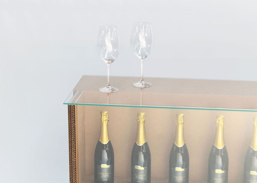 Comptoir en carton écologique pour stands événementiels ou aménagement de magasins, avec rangement transparent pour bouteilles de champagne et accessoires en verre élégants, idéal pour salons professionnels et décoration scénographique - Le Meuble en Carton une marque du groupe Natur Design