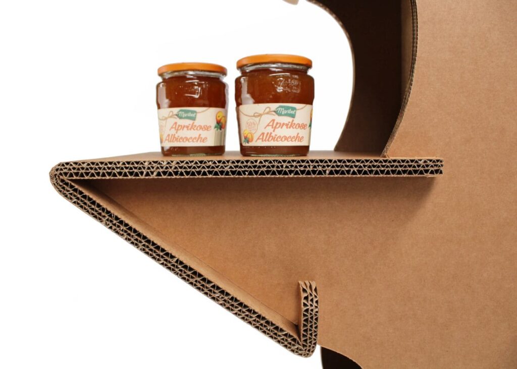 Présentoir en carton éco-responsable pour stands événementiels et décoration de magasins, avec plateau en carton structuré supportant des pots de confiture 'Aprikose Albicocche' pour mise en valeur visuelle dans un environnement professionnel ou commercial - Le Meuble en Carton une marque du groupe Natur Design
