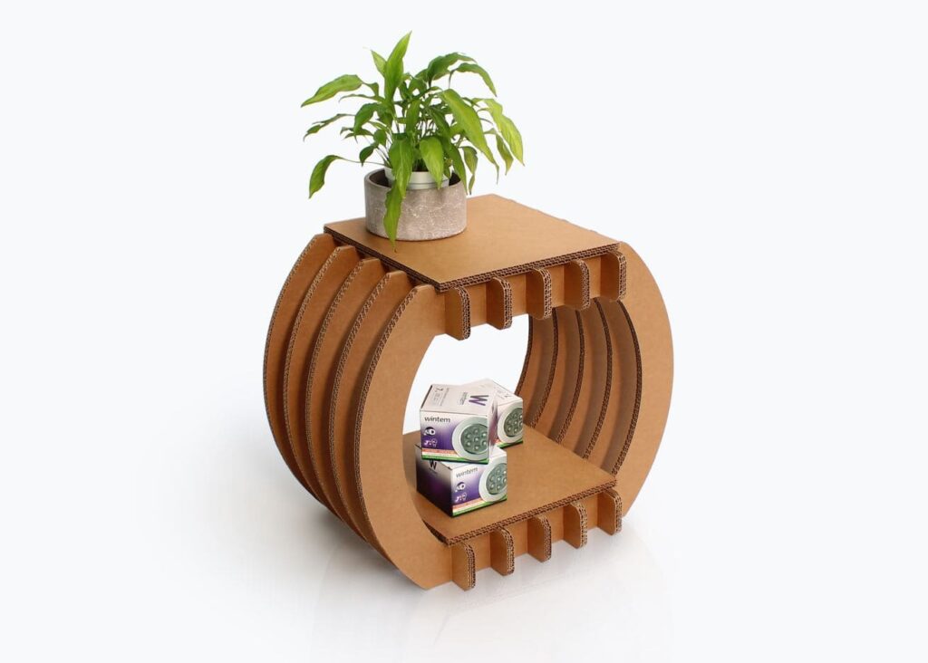 Étagère en carton design avec compartiments pour rangement d'articles de bureau, idéale pour les espaces modernes et écologiques comme les bureaux ouverts ou les salons professionnels. Plateforme supérieure intégrant une petite plante verte et des boîtes de produits logistiques ou office disposées dans les niches latérales - Le Meuble en Carton une marque du groupe Natur Design