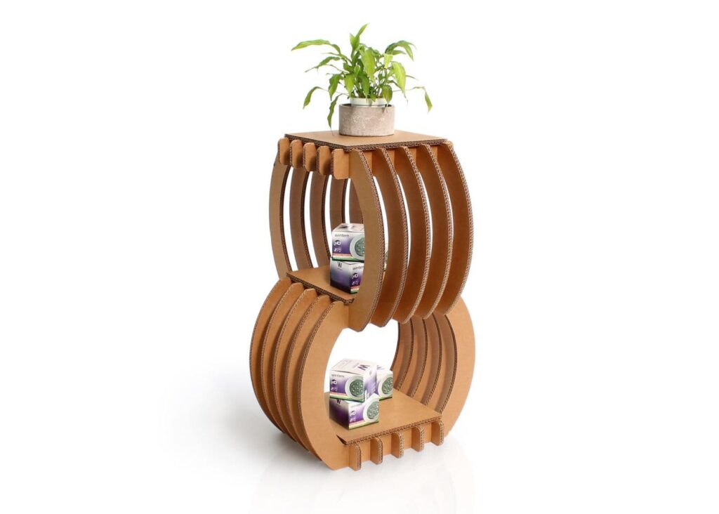 Étagère en carton design et écologique en forme de VINSON, présentoir modulable pour produits de bureau ou espaces professionnels avec plateaux et rangements ouverts, intégrant des éléments naturels comme une petite plante verte dans le haut - Le Meuble en Carton une marque du groupe Natur Design