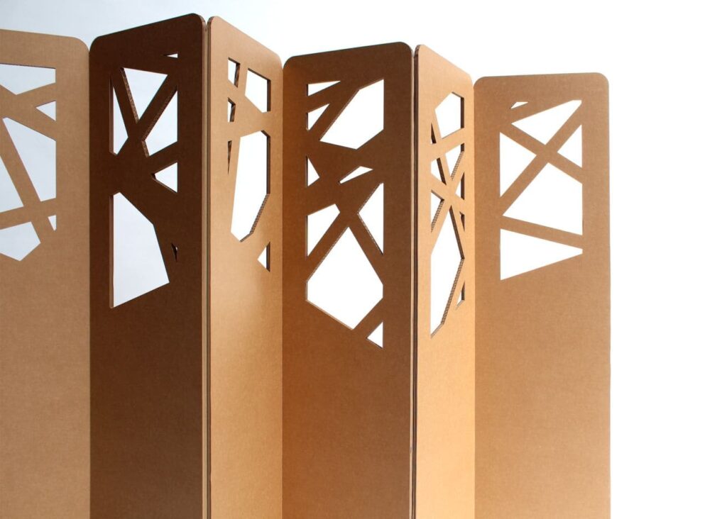 Paravent ajouré en carton écologique pour stands événementiels et décoration d'espaces professionnels, avec motifs géométriques inspirés de l'art minimaliste. Idéal pour aménager des espaces de travail en open space ou des zones dédiées aux salles de pause dans les entreprises - Le Meuble en Carton une marque du groupe Natur Design